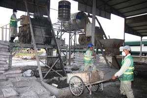 勞工將工業垃圾再製造成建材的原料。