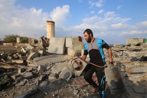 一名巴勒斯坦男子在加沙地帶城市拉法檢查空襲後的 廢墟。（圖源：新華社）