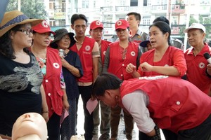 紅十字會人員指引民眾被異物卡住喉嚨的急救方法。