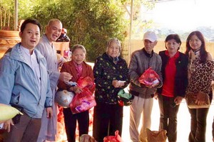 該廟慈善組組長鄒國榮（左一）與寶光浮寺的 振啟法師（左二）向少數民族同胞派發禮物。