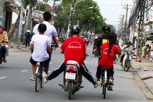 一輛摩托車推著２輛自行車在街上並排駕駛的情景要不得。