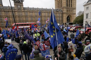 英國倫敦民眾在議會大廈外揮舞旗幟和標語牌。（圖源：新華社）