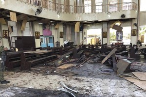 炸彈炸毀了教堂入口大門，教堂內的長椅和其他門都碎裂了，大廳一片狼藉。（圖源：AP）