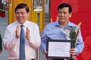 市人委會主席阮成鋒(左)向《西貢 解放報》副總編輯、華文《西貢解放日 報》主編阮玉英(紅藍)頒獎。