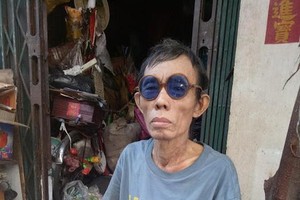 吳月貴拿著病案坐在自家門口。