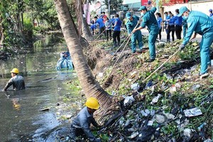 本市年輕人與都市排水人員配合清理第十二郡盛祿坊黏土渠上的垃圾。