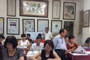 張路書畫家正在教學生練習書法。