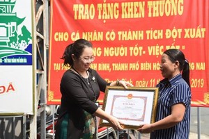 拾金不昧的賣彩票婦女黎氏厚（右）榮獲同奈省領導頒發的獎狀。（圖源：阮壬）