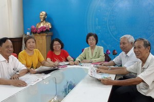 市各少數民族文學藝術協會主席劉金華（右三）與同事閱讀本報新聞。