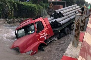 牽引車陷入路面塌陷的深水坑，坑水高漲淹沒部分車身。（圖源：Oto+）