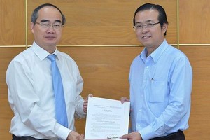 黎文明同志（右）從市委書記阮善仁手中接過調動和委任《決定》。（圖源：越勇）