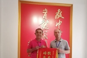 黃智球老師（左）代表本市華文老師團向組委會陳進超校長贈送紀念錦旗。