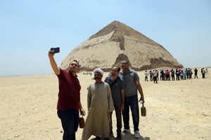 7月13日，人們在埃及首都開羅以南的彎曲金字塔前拍照。（圖源：新華社）
