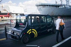 圖為水上交通碼頭前一位乘客走過無人駕駛小客車。（圖源：互聯網）