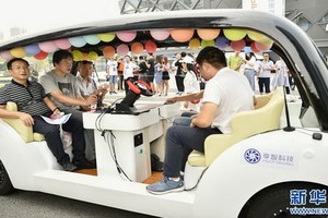 8月28日，在“5G自動駕駛科技示範體驗”活動現場，重慶市民在一輛自動駕駛汽車挑戰賽的參賽車輛上進行5G自動駕駛真實城市道路試乘體驗。（圖源：新華社）