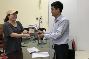 計程車公司代表將乘客遺失的錢包交還失主。（圖源：V.X）