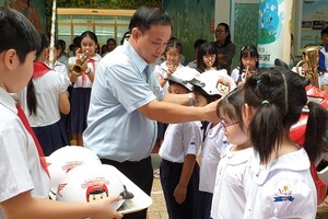 明道小學校長阮忠海給一年級小學生戴安全帽。