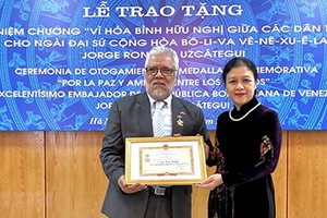 阮芳娥大使（右）代表VUFO領導向委內瑞拉共和國特命全權大使豪爾赫‧隆東‧烏斯卡特吉頒贈紀念章。（圖源：越通社）