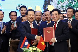 政府副總理、外交部長范平明（前右）與老撾外交部長沙倫塞‧貢瑪西簽署越南外交部與老撾外交部之間行動計劃。（圖源：外交部）