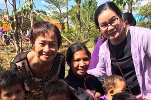 華人商販應氏蓮(後排左一)與貧困戶及兒童合影。