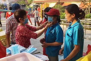 華人商販應氏蓮(左一)正在向消費者派發口罩。