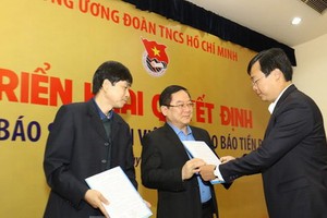 共青團中央書記處第一書記黎國鋒（右）向《前鋒報》總編輯黎春山頒發人事委任《決定》。（圖源：《前鋒報》）