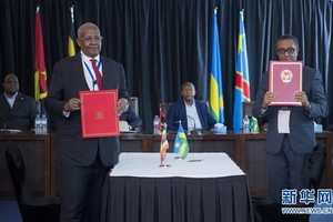 2月21日，烏干達外交部長庫泰薩（左）和盧旺達外交部長比魯塔（右）在兩國之間的加圖納-卡圖納邊境通道簽署引渡條約後拍照。（圖源：新華社）