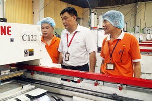 丁梅雄（中）與工人討論產品質量。