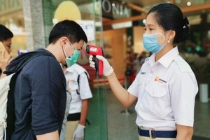 一個購物中心入口處，工作人員在檢查顧客的體溫。（圖源：互聯網）