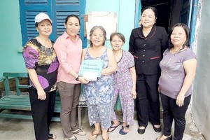 阮芳秋（左一）與地方幹部向窮困家庭發放輔助金。