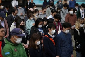 東京市民戴著口罩悼念“三‧一一”大地震逝者。（圖源：路透社）