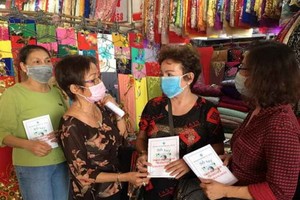 華人商販應氏蓮(左二)派發防疫手冊給商販。