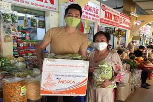 華人商販應氏蓮將防疫用品 交給阮飛雄歌星。