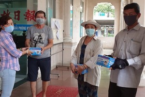 本報副執行編輯陳月寶(左一)代表向報販贈送口罩。