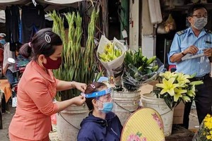 第五郡第十一坊婦女會主席 親自向商販戴上防護面罩。