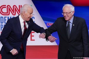 拜登（左）和桑德斯在電視辯論上以擊肘代替握手。（圖源：互聯網）