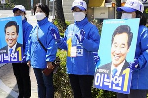 4月14日，首爾民眾在街頭手舉支持者海報號召投票。 （圖源：互聯網）