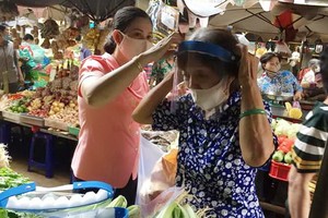 第十四坊婦女會主席向華人商販戴上防護面罩。