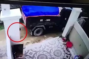 監控視頻顯示，站在車後的一名男童（紅圈示）不幸遭卡車倒車時輾壓當場死亡。（圖源：視頻截圖）