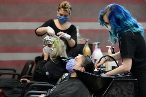 圖為美國佐治亞州瑪麗埃塔市的一家美髮店自24日重啟營業。（圖源：路透社）