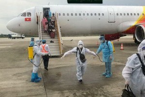 從印尼撤回的越南公民，乘客下機時接受噴灑消毒後送至集中隔離區進行醫學隔離觀察。（圖源：QCD）