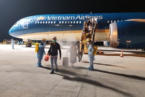 從阿拉伯聯合酋長國撤回的越南公民抵達芹苴機場下機時接受噴灑消毒。（圖源：VNA）