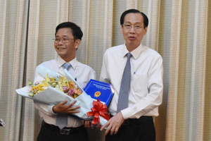 陳光草同志（左）從市人委會常務副主席黎清廉手中接過人事委任《決定》和祝賀鮮花。（圖源：進龍）