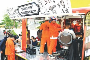 許多大學生在流動理髮車旁排隊等候理髮。