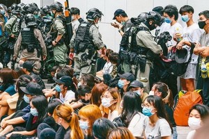 圖為香港警方留置抗議港版國安法的香港民眾後，打開他們的背包檢查。 （圖源：歐新社）