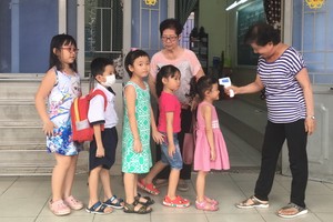 崇華華文中心老師向每班學生測量體溫。