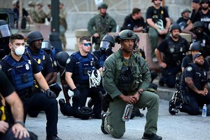 警察和遊行民眾跪地抗議針對非裔男子暴力執法的行為。（圖源：路透社）