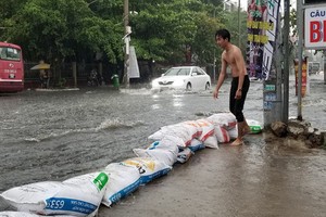 大雨導致守德郡的協平街淪為澤國，街道兩旁的民眾用麻袋來阻攔以避免雨水湧入住房。（圖源：黃燕）