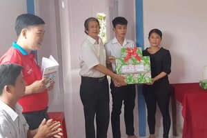 阮文菜老師在向阮陳日輝家庭贈送禮物分享入住新屋的喜悅。