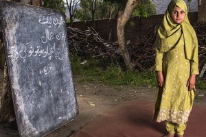 一名10歲的阿富汗女童站在已成廢墟的學校舊址前。（圖源：聯合國）